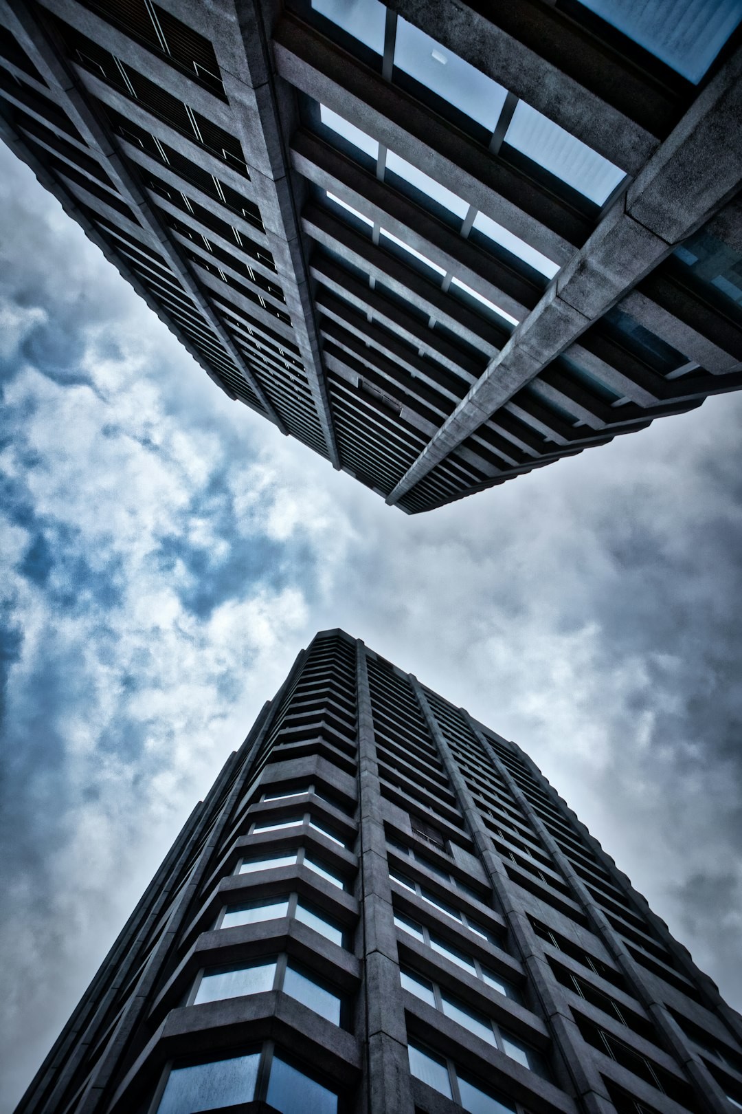 looking up at two tall buildings in a cloudy sky